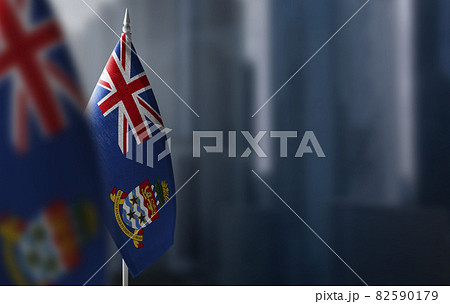 Small flags of Cayman Islands on a blurry background of the city 82590179