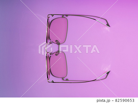 Stylish gold and pink eye glasses with shadow on purple and pink gradient background. Flat lay style, top view. Copy space for your text. Minimal summer concept. 82590653