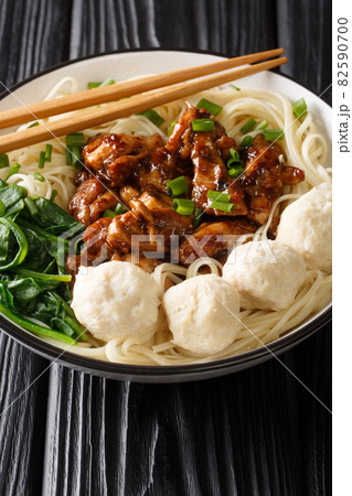 Mie ayam, mi ayam or bakmi ayam is a common Indonesian dish of seasoned noodles topped with diced chicken meat and meatball closeup in the bowl. Vertical 82590700