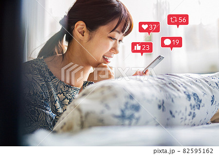 スマホでSNSを楽しむ若い女性 82595162
