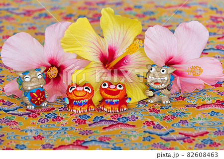 ミンサー織の上に乗るハイビスカスとシーサー 82608463