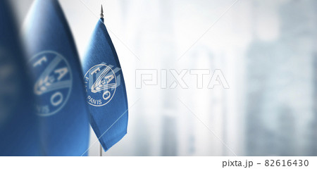 Small flags of Food and agriculture organization on a blurry background of the city 82616430