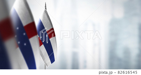 Small flags of Netherlands Antilles on a blurry background of the city 82616545