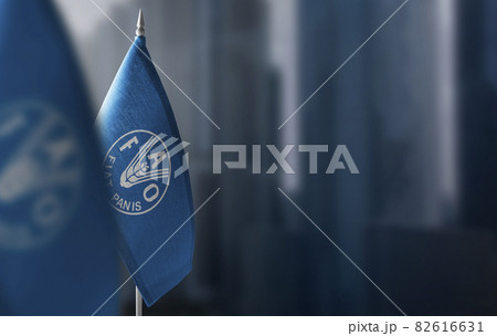 Small flags of Food and agriculture organization on a blurry background of the city 82616631