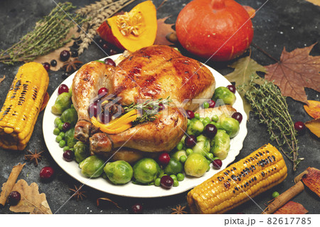 Thanksgiving turkey or chicken for a festive dinner. Food table background with autumn seasonal specialties for Thanksgiving Day. Fried chicken with pumpkin, vegetables and autumn decor on a wooden 82617785