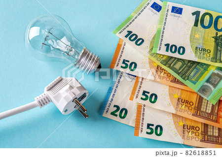 White electric plug, light bulb and euro money banknotes over blue background. White electric plug, light bulb and euro money banknotes over blue background. 82618851