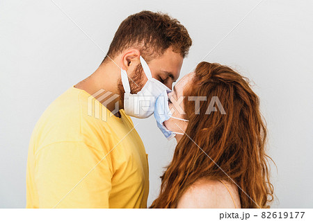 A couple loves and miss eachother and trying to kiss with medical protaction mask. Health care and pandemic. A couple loves and miss eachother and trying to kiss with medical protaction mask. Health care and pandemic. 82619177