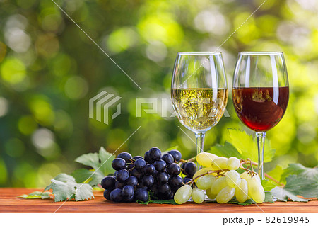 two glasses of red and white wine on table in garden 82619945