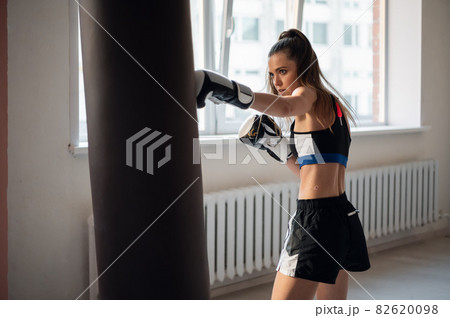 Beautiful woman boxing combat bag with sport trainer together. Girl boxer exercising box punch with personal coach. Beautiful woman boxing combat bag with sport trainer together. Girl boxer exercising box punch with personal coach. 82620098