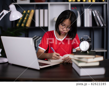 Smart asian girl child sit at table study at laptop make notes write in notebook, schoolgirl handwrite prepare homework assignment, prepare task at home, distant education concept 82622285