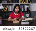 girl holding mobile phone sitting in a chair in the reading room. 82622287