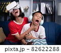 Little boy has fun wearing vr goggles while girl is playing mobile phone. 82622288