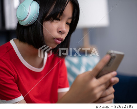 girl wearing headphones using smartphone, interested child listening to favorite music, chatting in social network or playing game online. girl wearing headphones using smartphone, interested child listening to favorite music, chatting in social network or playing game online. 82622295