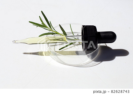 Essential oil with rosemary leaves in petri dishes on white background. 82628743