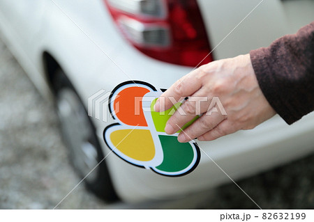 車に高齢者マークを貼るシニアの女性の手の写真素材