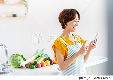 キッチンに立つ笑顔のミドル女性 82633897