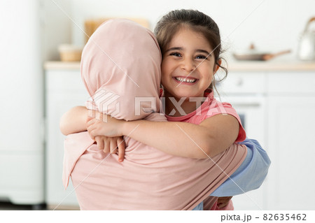 Happy Little Girl Embracing Her Muslim Mom In Hijab At Home, Closeup 82635462