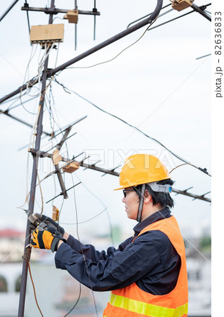 Asian worker repairing an old TV antenna on rooftop 82636833