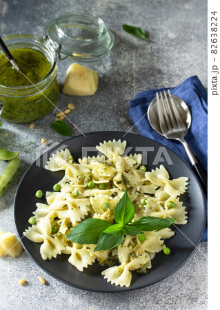 Healthy Italian cuisine. Pasta with green peas and pesto sauce in black bowl on grey stone background. Healthy Italian cuisine. Pasta with green peas and pesto sauce in black bowl on grey stone background. 82638224