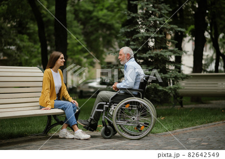 Daughter and disabled father resting on a bench Daughter and disabled father resting on a bench 82642549