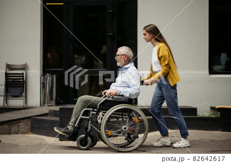 Daughter and disabled father go for a walk Daughter and disabled father go for a walk 82642617