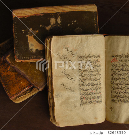 Stack of open ancient books in Arabic. Old Arabic manuscripts and texts. Top view Stack of open ancient books in Arabic. Old Arabic manuscripts and texts. Top view 82643550