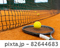 Close up tennis ball, racket and net on court. Close up of tennis ball on clay court. Red clay court. 82644683
