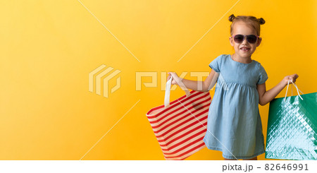 Banner Portrait Beautiful Happy Little Preschool Girl In Sunglasses Smiling Cheerful Holding Cardboard Bags Isolated On Orange Yellow Background. Happiness, Consumerism, Sale People shopping Concept Banner Portrait Beautiful Happy Little Preschool Girl In Sunglasses Smiling Cheerful Holding Cardboard Bags Isolated On Orange Yellow Background. Happiness, Consumerism, Sale People shopping Concept 82646991