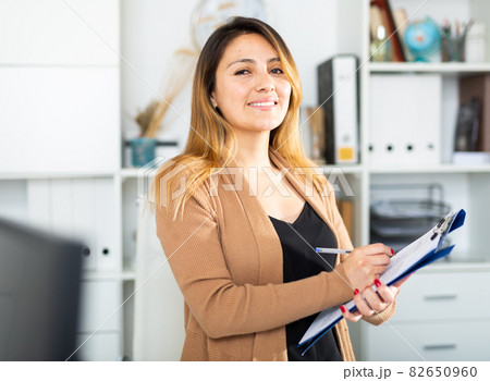 Young colombian woman manager holding clipboard Young colombian woman manager holding clipboard 82650960