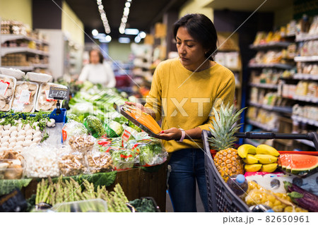 Female shopper chooses ripe radish at supermarket Female shopper chooses ripe radish at supermarket 82650961