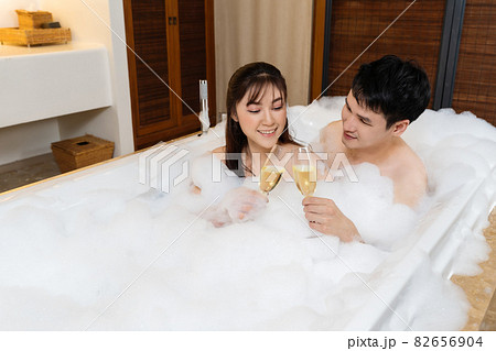 relaxed couple drinking wine from glass while enjoying bubble bath in bathtub relaxed couple drinking wine from glass while enjoying bubble bath in bathtub 82656904