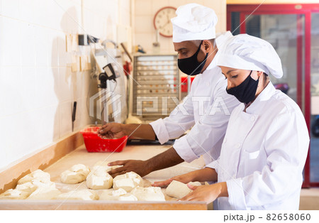 Male and female baker in protective mask working together in bakery 82658060
