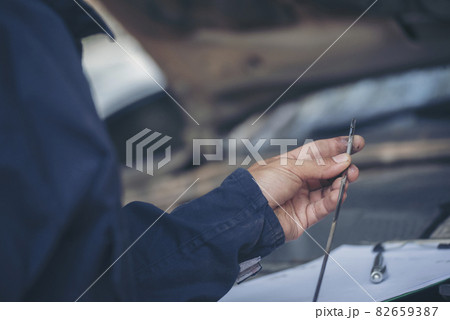 Car Mechanic man hand checking dipstick engine oil car mechanical on site service. Close up hand man check engine oil level Locate dipstick, wipe clean, check dipstick level before fill up engine oil 82659387