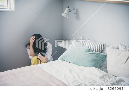 ベッド脇で頭を抱える女性 頭を抱える人 落ち込む女性 82660954