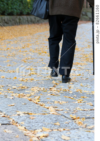 落ち葉を踏みしめる老婆 82661160