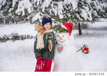 Happy blonde cute child girl plaing with a snowman 82661339