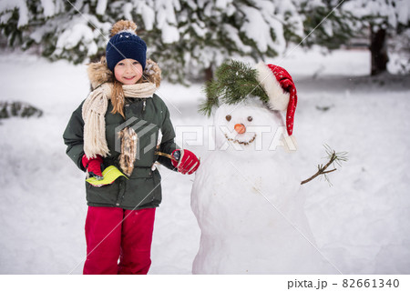 Happy blonde cute child girl plaing with a snowman 82661340