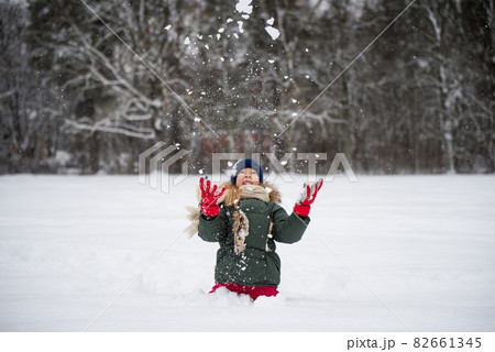 Happy child girl plaing with snow on a snowy winter walk 82661345