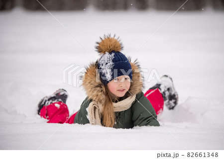Happy child girl plaing with snow on a snowy winter walk 82661348