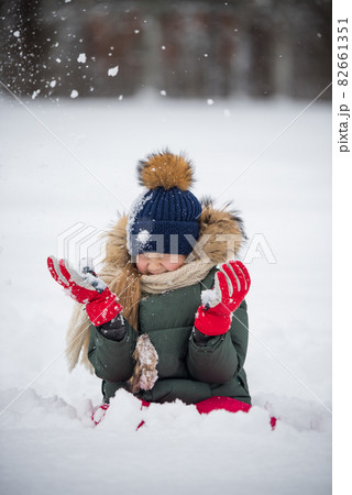 Happy child girl plaing with snow on a snowy winter walk 82661351