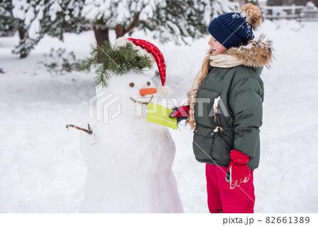 Happy blonde cute child girl gives a letter to a snowman 82661389