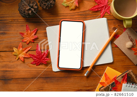Smart phone, notebook, coffee cup, pine cone and Autumn maple leaves on wooden table. 82661510