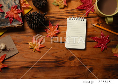 Empty notepad, coffee cup, pine cone and maple leaves on wooden table. Empty notepad, coffee cup, pine cone and maple leaves on wooden table. 82661511