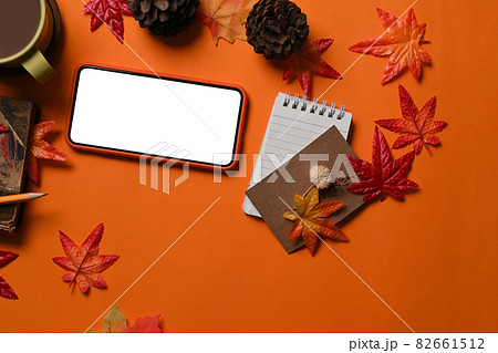 Smart phone, notebook, coffee cup, pine cone and Autumn maple leaves on orange background. 82661512