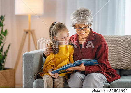 Grandmother reading a book to granddaughter. 82661992