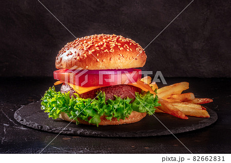 Classic beef burger with French fries, a side view on a black background Classic beef burger with French fries, a side view on a black background 82662831