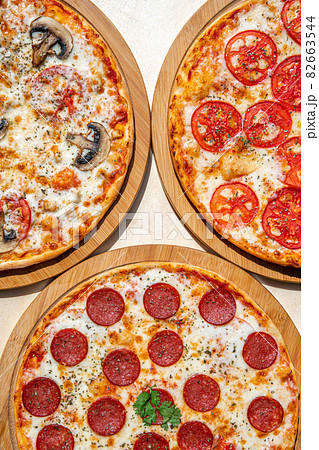 Delicious italian pizzas served on wooden table. Delicious italian pizzas served on wooden table. 82663544