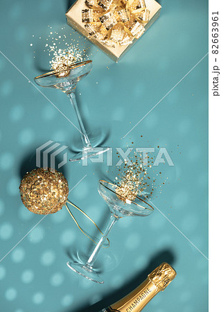 Two champagne glasses with splash of confetti, gifts and decorations over creative background Two champagne glasses with splash of confetti, gifts and decorations over creative background 82663961