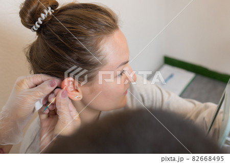 Professional holding the jewel of piercing just before screw the ball. 82668495