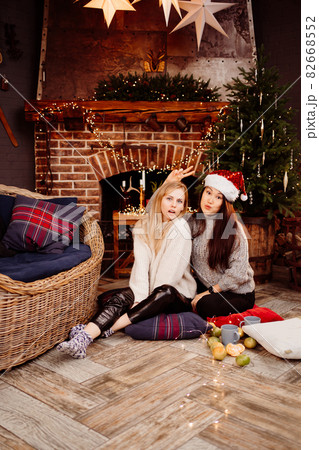 cheerful girlfriends in the New Year's decorations in the fireplace cheerful girlfriends in the New Year's decorations in the fireplace 82668552